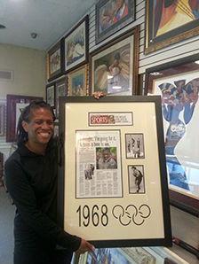 A man proudly holds a framed picture of the Olympics