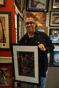 A man smiles while holding a framed picture in a store